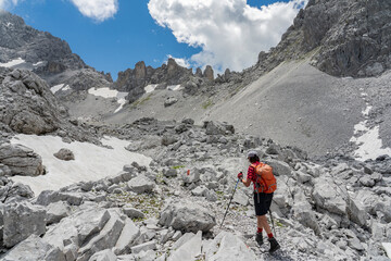 senior woman hiking in the wild terrain  below the Drosa Tor in the  mountains of Montafon valley, Vorarlberg, Austria