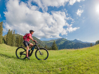 active senior woman riding her electric mountain bike in the Allgau Alps near city of Immenstadt, Algäu, Bavaria, Germany