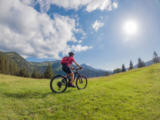 Naklejka na ściany i meble active senior woman riding her electric mountain bike in the Allgau Alps near city of Immenstadt, Algäu, Bavaria, Germany