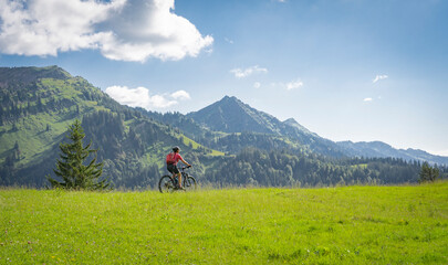 Fototapeta na wymiar active senior woman riding her electric mountain bike in the Allgau Alps near city of Immenstadt, Algäu, Bavaria, Germany
