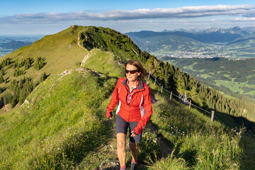 pretty senior woman hiking in the early evening in warm dawn light on the ridge of the Nagelfluh...