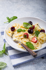 Curly bow-shaped paste with basil, berry on concrete table