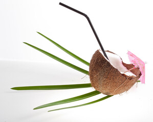 Coconut pieces with palm leaves, cocktail umbrella and straw isolated on a white background.