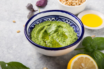 Homemade basil pesto with pine nuts, parmesan and garlic. Green pesto sauce in a bowl, top view