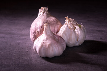 three large heads of pink garlic on a kitchen worktop