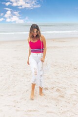 Beautiful short haired model posing for photos on the beach. Wearing jeans and a pink blouse.