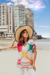 Beautiful short haired model posing for photos on the beach. Wearing jeans and colorful blouse.