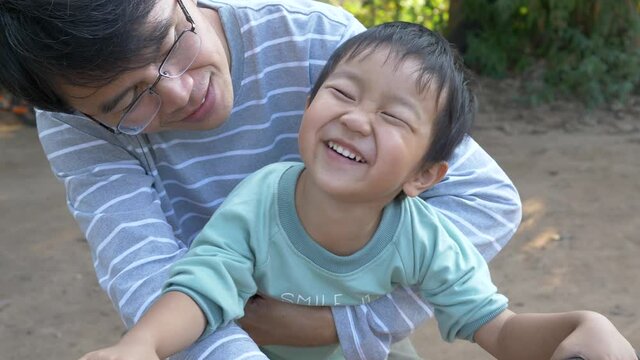 4K Asian child boy and dad in happy moment shot, smiling with happy cute face outdoor, hug and kiss with love. Father's day and son concept, slow motion shot.