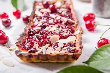 Beautiful freshly made cherry tart decorated with almond chips. Food photography.