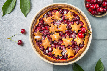 Homemade open cherry pie with frech cherries  on a gray concrete background.