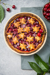 Homemade open cherry pie with frech cherries  on a gray concrete background.