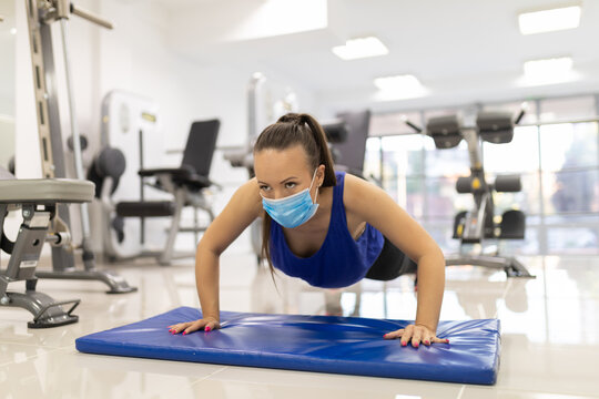 Woman have indoor training in gim with medical facemask push-ups. Female breathes deeply stock photo