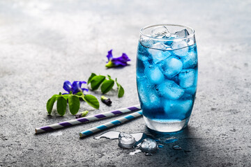 Blue butterfly pea flower herbal tea for healthy drinking on grey concrete background.