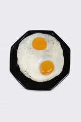 Close up of two delicious fried eggs on a plate ready to eat isolated on a white background