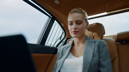 Surprised business woman using laptop at backseat. Businesswoman smiling at car