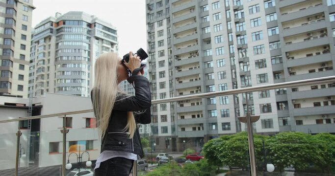 Mixed race blond woman tourist taking a photo in the city during the day. Skyscrappers architecture background