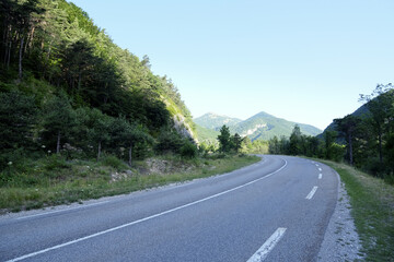 Mountain road in French Alpes on a sunny summer morning, beautiful natural landscape for travel design, empty rural road with picturesque scenery