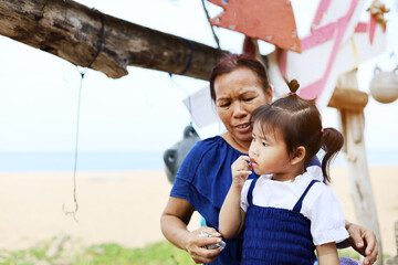 Beautiful Asia Grandma and girl are on the beach in holiday weekend at Phuket, Thailand.