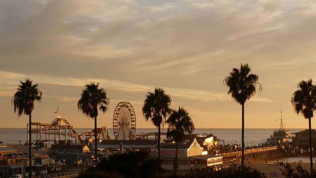 Fototapeta Classic ferris wheel, amusement park on pier in Santa Monica pacific ocean beach resort. Summertime California aesthetic, iconic view, symbol of Los Angeles, CA USA. Sunset golden sky and attractions