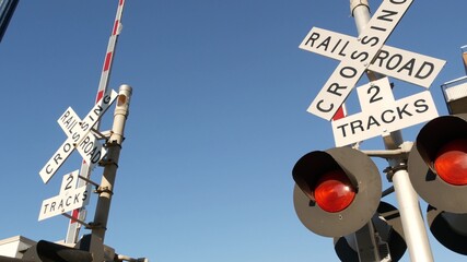 Level crossing warning signal in USA. Crossbuck notice and red traffic light on rail road...