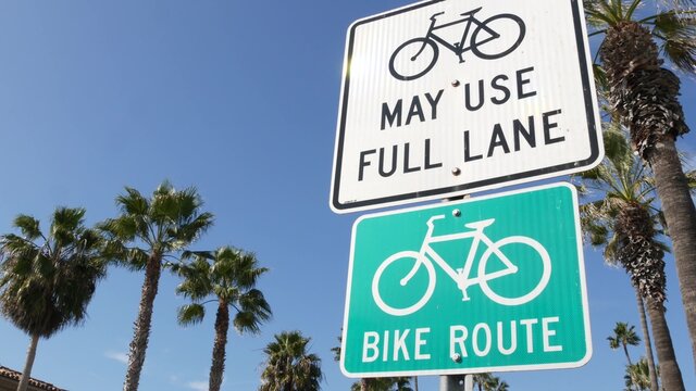 Bike Route green road sign in California, USA. Bicycle lane singpost. Bikeway in Oceanside pacific tourist resort. Cycleway signboard and palm. Healthy lifestyle, recreation and safety cycling symbol