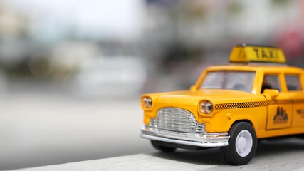 Yellow vacant mini taxi cab close up, Harmon corner, Las Vegas, USA. Small retro car model on defocused background. Little iconic auto toy as symbol of transport in soft focus. Blurred shopping mall