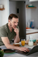 Fototapeta na wymiar Handsome man preparing breakfast at home. Young man drinking coffee in kitchen. 