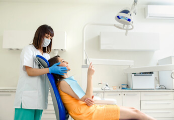 Dentist is showing to her patient the new smile in the mirror