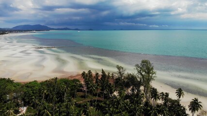Unusual coast of white sand. Breathtaking landscape of sandy wavy seaside. Paradise islands in Asia. Drone view, natural idyllic scene, coconut palms on the beach. Thunderstorm in the tropics.