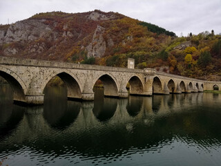 Fototapeta na wymiar Beautiful old stone bridge over the river reflecting in the water