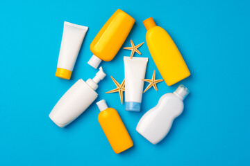 Sunscreen cream bottles with sea shells on blue background