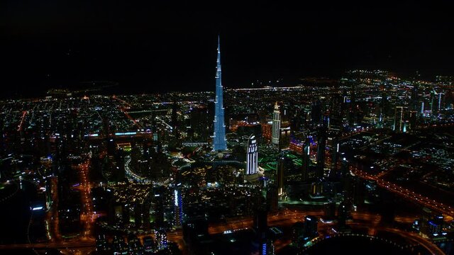 A magnific aerial view of the Burj Khalifa and of the Downtown Dubai neighborhood at night including a view of the Sheikh Zayed Road, pan right, 6-axis stabilized gimbal, Shotover F1, 8K, parallax.