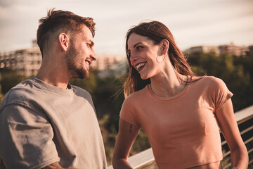 Foto di una giovane coppia di fidanzati che si scambiano sguardi di amore e complicità al tramonto 