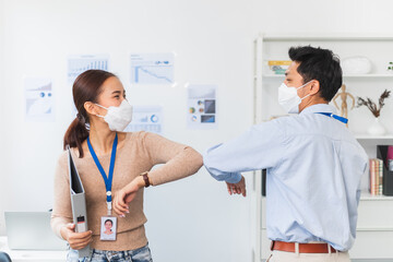 Asian businessman greeting with elbow bump or shaking elbow in working office to avoid touching due to infection of coronavirus covid-19, new normal life and social distancing concept