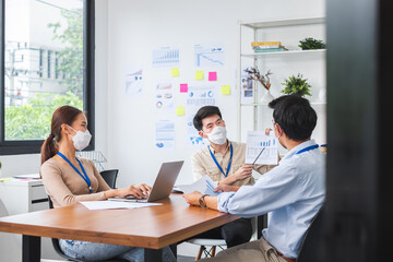 Asian business people wear face mask working and meeting in office to protect infection of coronavirus covid-19, reopen business with new normal and social distancing concept