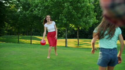 Fototapeta premium Children and parents playing with ball in meadow. Family having fun together