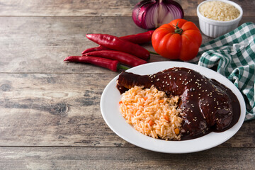 Traditional mole Poblano with rice in plate on wooden table. Copy space