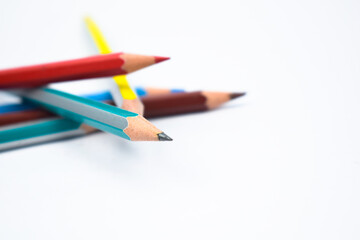 Five different colored wood pencil crayon scattered on a white background