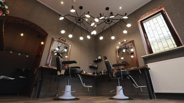 Barbershop room with two working places in the beauty salon. Hair salon interior. Empty chairs in styled barbershop. Chairs and mirrors in modern hairdressing. Interior of a modern hair salon
