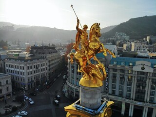 Beautiful aerial drone photography. Country Georgia from above. Capital Tbilisi. Liberty square and close up portrait of  saint George golden monument. - obrazy, fototapety, plakaty