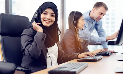 Fototapeta premium Muslim woman work as call center. Customer service executive working at office. Young friendly operator woman agent with headsets working in call centre. Clean office concept