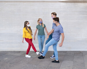Obraz premium Happy multiracial friends meet and greet each other with their feet - Young people wearing protective face mask - Concept of social distance, safety measures and health care