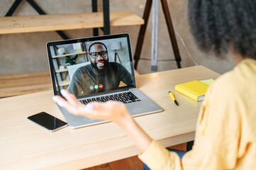 Back view of biracial girl talks via video call with an african-american male colleague or friend...