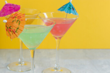 Glasses of various delicious fruit non-alcoholic cocktails on a bright background with umbrellas. Health drinks.