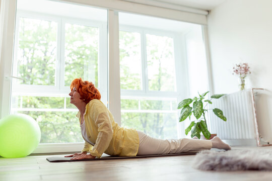 Active senior woman doing yoga session at home