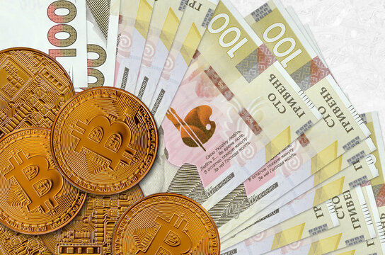 100 Ukrainian hryvnias bills and golden bitcoins. Cryptocurrency investment concept. Crypto mining or trading