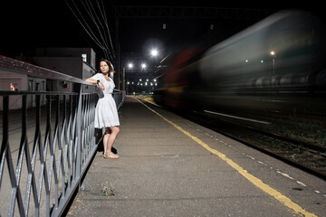 A girl stands at night at the railway station