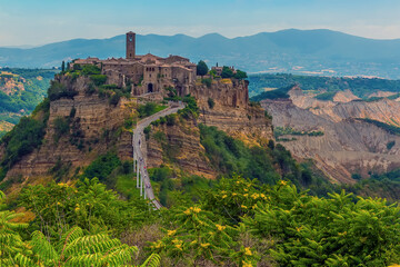 Fototapeta na wymiar A view towards the entrance bridge for the hill top settlement of Civita di Bagnoregio in Lazio, Italy in summer
