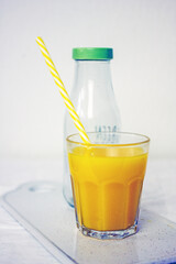 Freshly squeezed orange juice in a bottle with a glass
