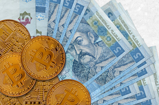 5 Ukrainian hryvnias bills and golden bitcoins. Cryptocurrency investment concept. Crypto mining or trading